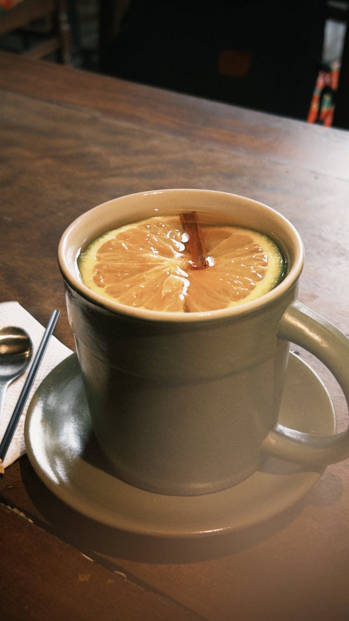 Angebote A cozy ceramic mug filled with lemon tea and cinnamon, sitting on a wooden table.